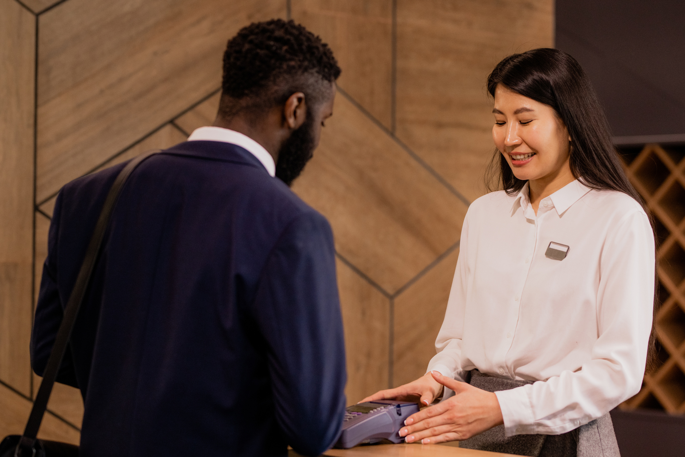 Happy Young Hotel Receptionist Serving a Guest